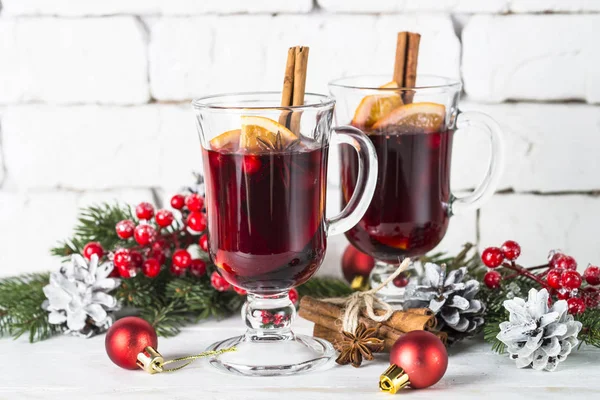 Mulled wine in glass mug with fruit and spices on white.