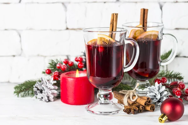 Vin chaud dans une tasse en verre avec fruits et épices sur blanc . — Photo