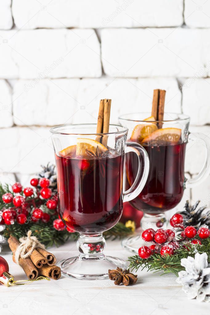 Mulled wine in glass mug with fruit and spices on white.