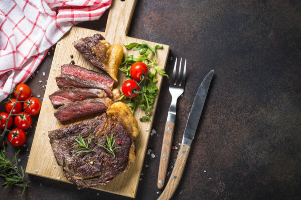 Grilled beef steak ribeye on wooden cutting board. 