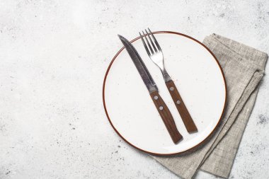 Beyaz zanaat tabak, çatal ve peçete beyaz taş masada. 