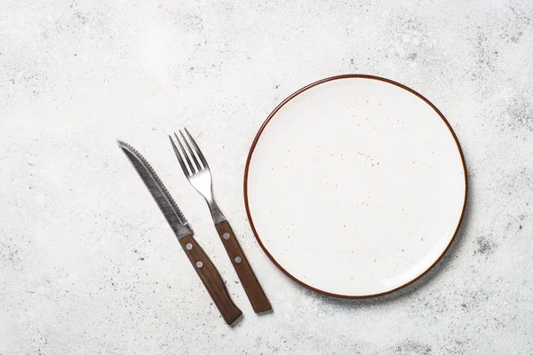 Assiette artisanale blanche, couverts et serviette sur table en pierre blanche . — Photo