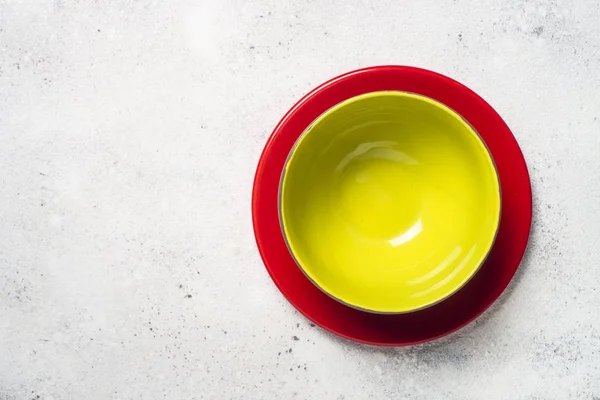 Colored dinnerware - red and green plates on light stone table. — Stock Photo, Image