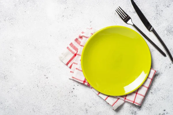 Green plate, cutlery and tablecloth on light stone table. — Stock Photo, Image