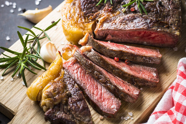 Grilled beef steak ribeye medium rare on wooden cutting board. Close up.