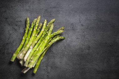 Siyah arduvaz arka plan üzerine taze yeşil kuşkonmaz.