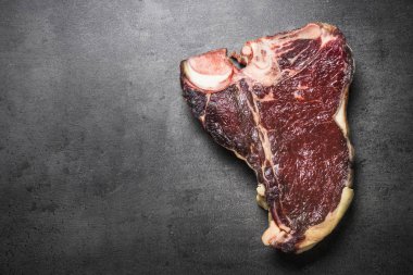 Kuru yaşlı sığır eti biftek t-bone siyah arduvaz arka planda. Üstten görünüm.