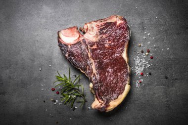 Kuru yaşlı sığır eti biftek t-bone siyah arduvaz arka planda. Üstten görünüm.