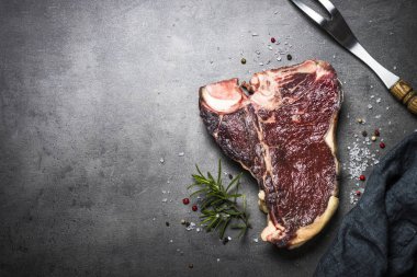 Kuru yaşlı sığır eti biftek t-bone siyah arduvaz arka planda. Üstten görünüm.