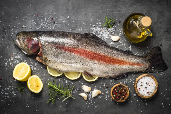 Raw salmon fish whole with ingredients for cookings on black. — Stock Photo, Image