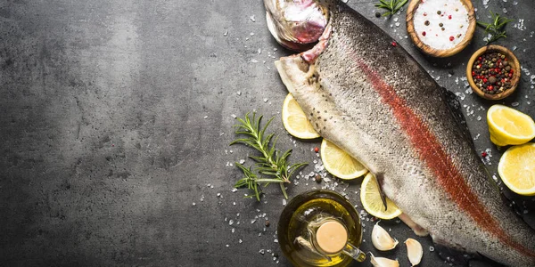 Rauwe zalm vis geheel met ingrediënten voor cookings op zwart. — Stockfoto