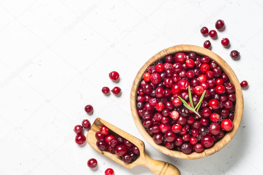 Cranberry in wooden bowl on white background.