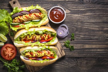 Sosisli sandviç ahşap masa üzerinde taze sebze ile.