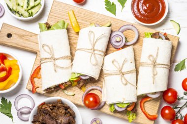 Sığır eti ve sebze üzerinde beyaz backgr ile burrito tortilla saran