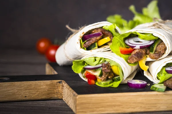 Burritos tortilla wraps with beef and vegetables on wooden close — Stock Photo, Image