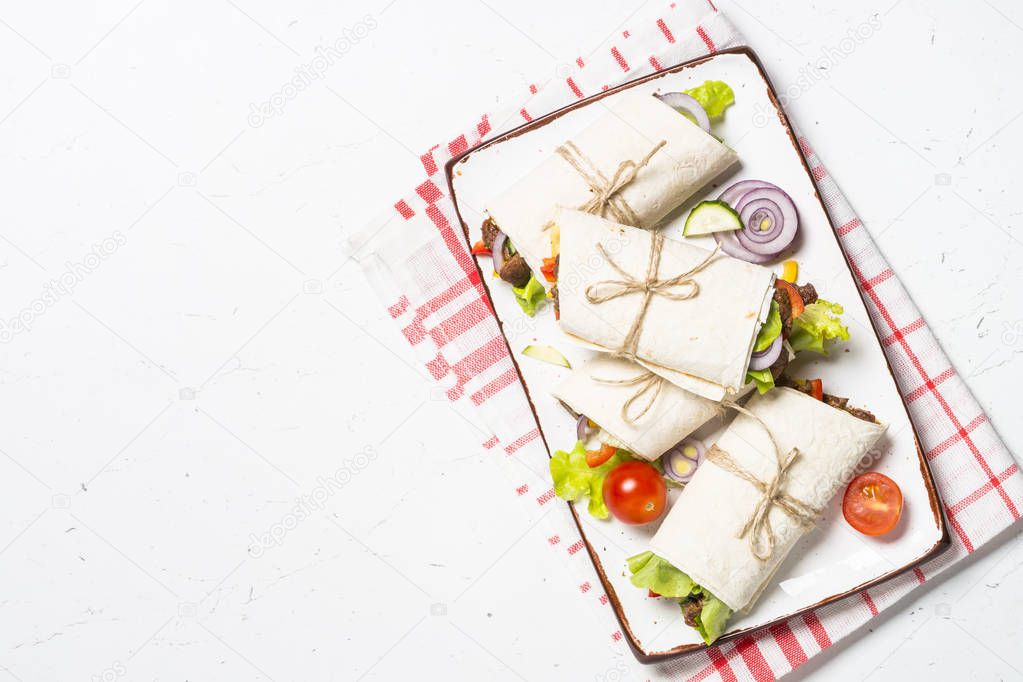 Burritos tortilla wraps with beef and vegetables on white backgr