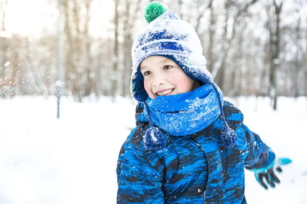 Šťastné dítě chlapec hrající sněhové koule venkovní. — Stock fotografie
