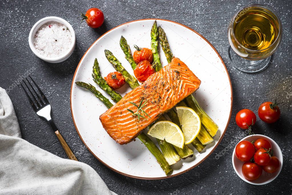 Baked salmon fish fillet with asparagus and tomato top view.