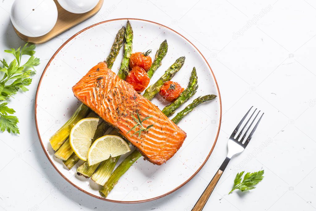 Grilled salmon fish fillet with asparagus on white. 