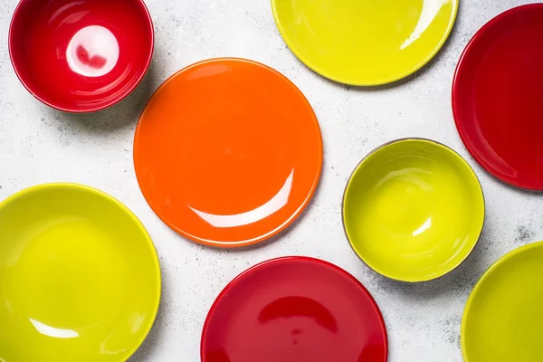 Colored dinnerware - red and green plates on light stone table. — Stock Photo, Image