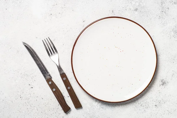 Beyaz zanaat tabak, çatal ve peçete beyaz taş masada. 