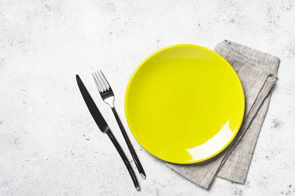 Green plate, cutlery and tablecloth on light stone table. — Stock Photo, Image