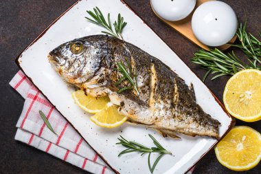 Limon ve biberiye karanlık taş masada dorado balık fırında. Üstten görünüm, kopya alanı.