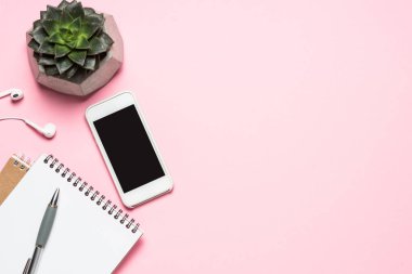 Ev Ofis İşyeri ile akıllı telefon, klavye ve kaktüs üzerinde pembe üstten görünüm. 