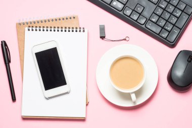 Not defteri, kahve fincanı ve pembe bir arka plan üzerinde klavye ile Ofis İşyeri.