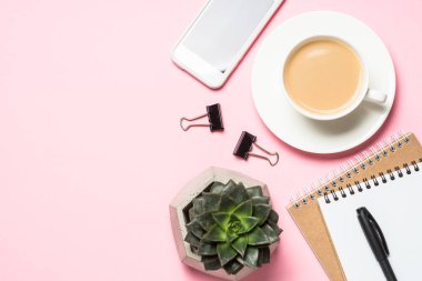 Boş not defteri, smartphone ve kaktüs üzerinde pembe üstten görünüm. 