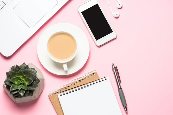 Oficina de trabajo con bloc de notas, taza de café y teclado sobre fondo rosa . —  Fotos de Stock