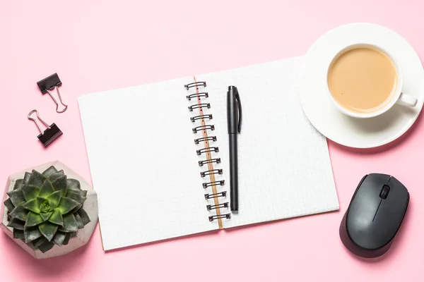 Posto di lavoro ufficio con blocco note, tazzina da caffè e tastiera sulla scrivania rosa . — Foto Stock
