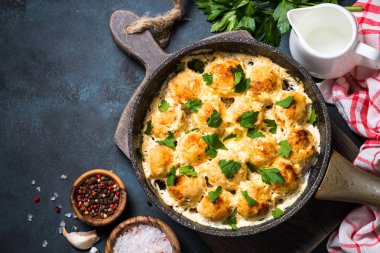 Karanlık taş masa üstü üzerinde krema soslu köfte görüntülemek.