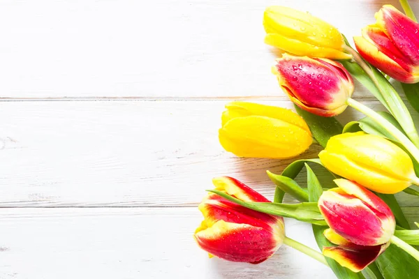 Tulips on white wooden table.