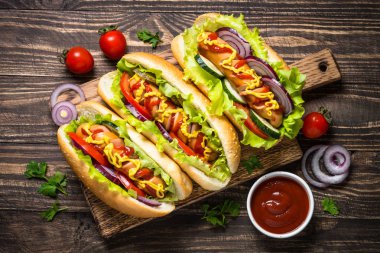 Sosisli sandviç ahşap masa üzerinde taze sebze ile.