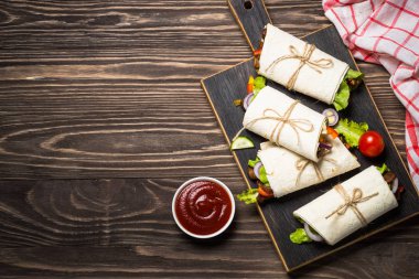 Sığır eti ve sebze ahşap arka plan üzerinde burrito tortilla saran.