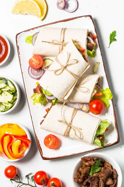 Burritos tortilla wraps med nötkött och grönsaker på vit bakgrund. — Stockfoto