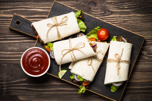 Burritos tortilla wraps med nötkött och grönsaker på trä bakgrund. — Stockfoto