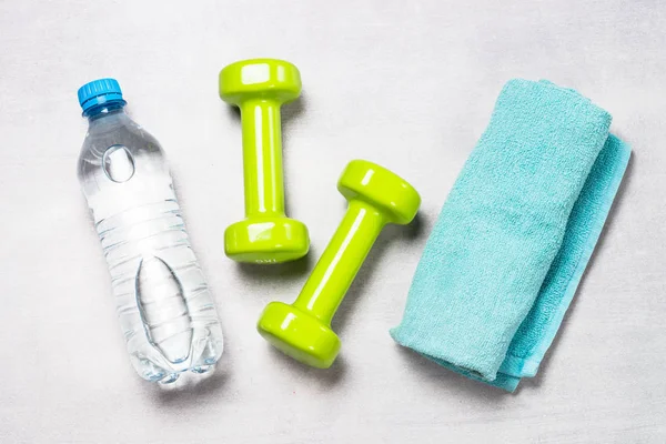Dumbbells, water and towel on light background top view. — Stock Photo, Image