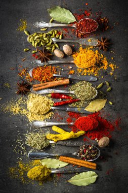 Siyah arka plan üzerine kaşık içinde baharatlar.