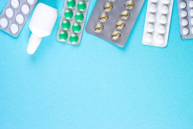 Tabletler ve ilaçlar üzerinde mavi bir arka plan.