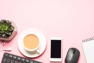 Not defteri, kahve fincanı ve pembe bir arka plan üzerinde klavye ile Ofis İşyeri.