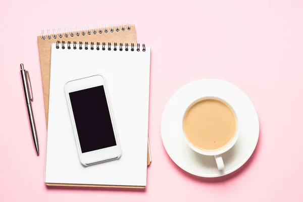 Inicio Oficina con bloc de notas, smartphone y taza de café en escritorio rosa . —  Fotos de Stock