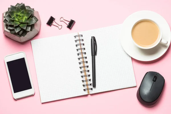 Büroarbeitsplatz mit Notizblock, Kaffeetasse und Tastatur auf rosa Schreibtisch. — Stockfoto