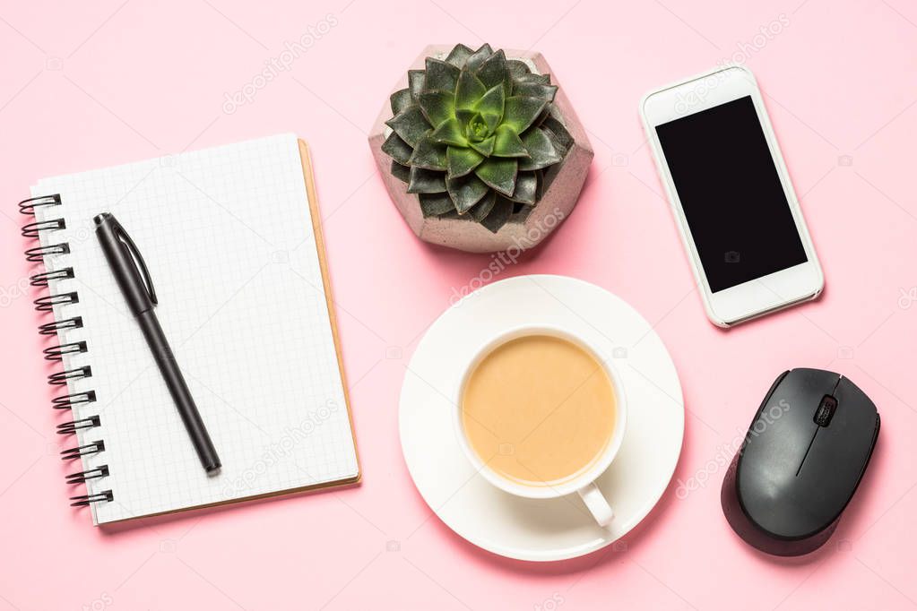 Freelance workplace with notepad, coffee cup, succulent and mouse on pink