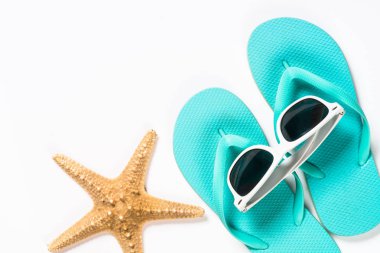 Mavi flip flop, güneş gözlüğü ve denizyıldızı mavi zemin üzerine.