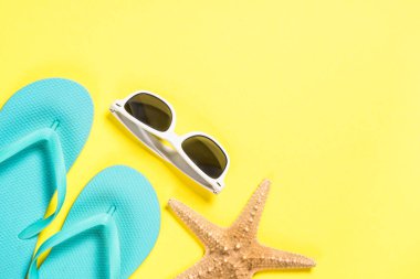 Mavi flip flop, güneş gözlüğü ve denizyıldızı üzerinde sarı Üstten Görünüm.