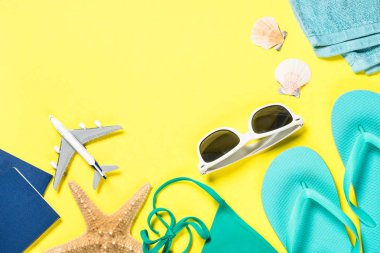 Mavi flip flop, güneş gözlüğü, pasaport, uçak ve Sarı zemin üzerine deniz yıldızı.