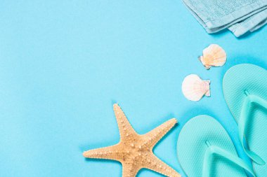 Mavi flip flop, havlu ve denizyıldızı mavi zemin üzerine.