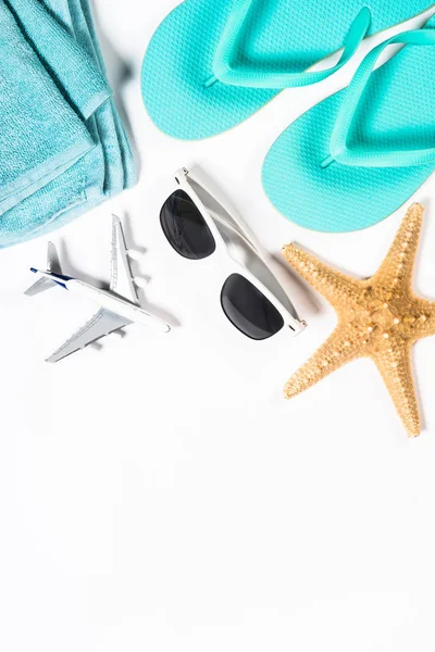 Chanclas azules, gafas de sol, avión y estrellas de mar sobre fondo blanco . — Foto de Stock